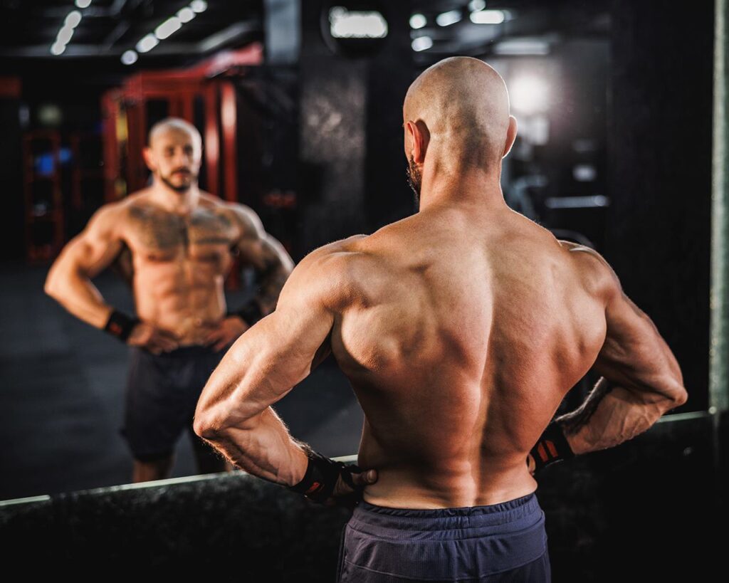 un-athlte-torse-nu-aux-muscles-toniques-pose-dans-la-salle-de-sport